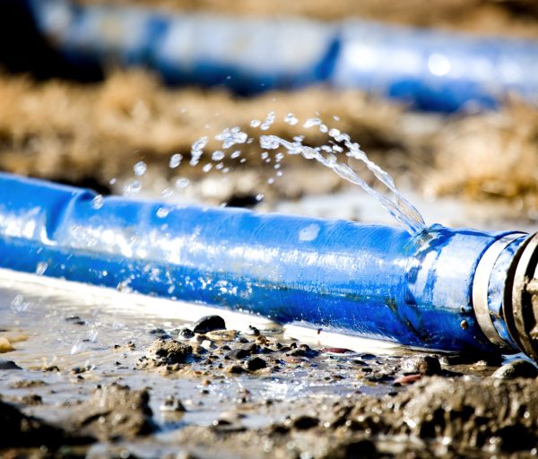 wasting water - water leaking from a hole in a hose. shallow dof with focus on leak